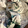 Kacen is registered to the contest to win money with this photo: baby, blanket, clothing, dinosaur, footwear, furniture, infant, mittens, pajamas, plush, sleepwear, soft, toddler, toy, wearing, lying_down, cozy, fabric, pattern, comfort