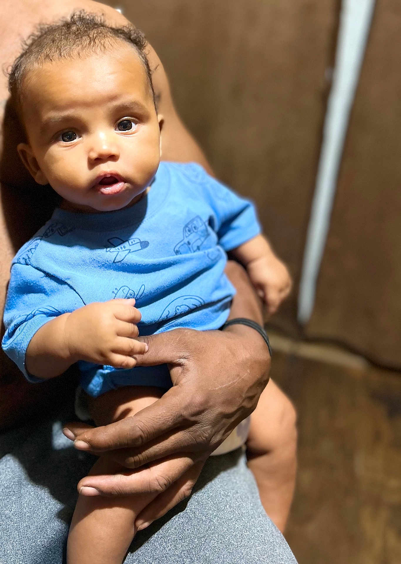 Kacen is registered to the contest to win money with this photo: baby, child, infant, person, blue_shirt, hand, adult_hand, indoor, portrait, cute, curious, seated, skin, face, eyes, expression, closeup, human, holding, casual
