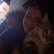 Faith is registered to the contest to win money with this photo: person, cat, tabby_cat, indoor, dim_light, snuggling, cozy, face, hair, couch, blurred_background, closeup, pet, animal, feline, companion, relaxed, portrait, happy, home