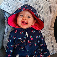 Leyna participe au concours pour gagner de l'argent avec cette photo : baby, cheerful, child, clothing, couch, cute, face, floral_pattern, happy, hoodie, indoor, infant, navy_blue, person, pillow, pink, portrait, seated, smiling, young