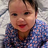 baby, child, smiling, face, hand, clothing, onesie, blue, floral_pattern, blanket, indoor, portrait, infant, cute, happy, person, young, bedroom, furniture, dresser