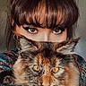 animal, bangs, brown_hair, calm, cat, closeup, colorful_clothing, eyes, face, feline, fluffy, indoor, intense_gaze, long_hair, looking_at_camera, orange_eyes, person, pet, portrait, whiskers