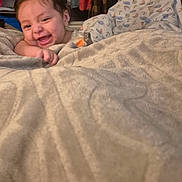 Kiran joined the competition — help win amazing prizes! baby, smiling, blanket, indoor, happy, child, face, cozy, clothing, portrait, home, person, cute, infant, toddler, relaxed, funny_hair, expression, lying_down, warm