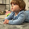 Shelby joined the competition — help win amazing prizes! toddler, child, portrait, face, eyes, hair, brown_hair, blue_clothing, pajamas, sitting, lying_down, carpet, indoor, home, furniture, shelf, soft_lighting, close_up, cozy, baby
