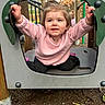 toddler, child, playground, smiling, happy, outdoor, portrait, play_equipment, pink_sweater, black_pants, blonde_hair, face, eyes, hands, sitting, autumn, trees, wood, adventure, daylight