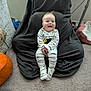 baby, child, smile, onesie, spider_web, pumpkin, blanket, carpet, chair, indoor, happy, cute, person, floor, cozy, clothing, head, feet, home, sitting