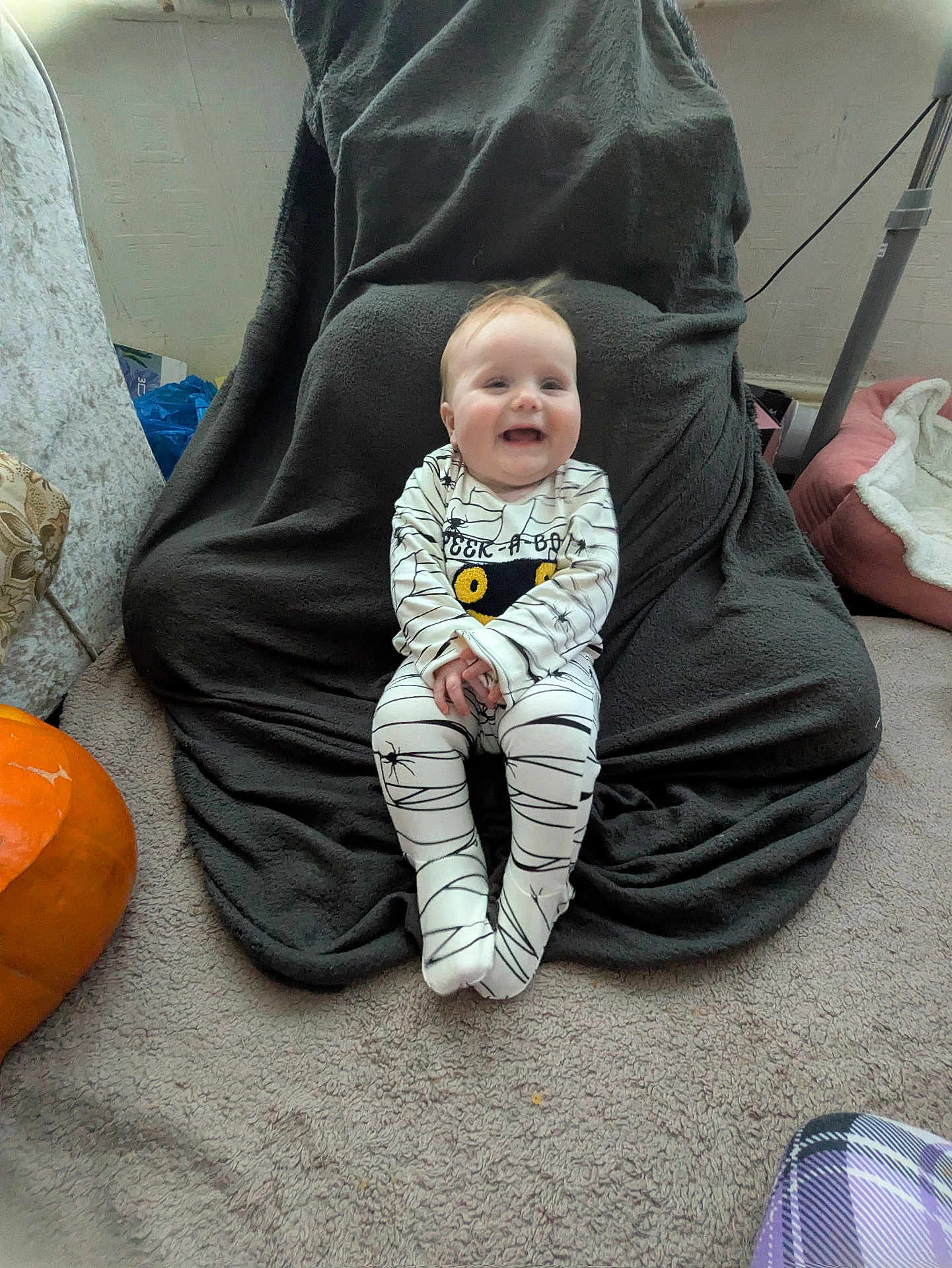 Elodie-Mae joined the competition — help win amazing prizes! baby, child, smile, onesie, spider_web, pumpkin, blanket, carpet, chair, indoor, happy, cute, person, floor, cozy, clothing, head, feet, home, sitting