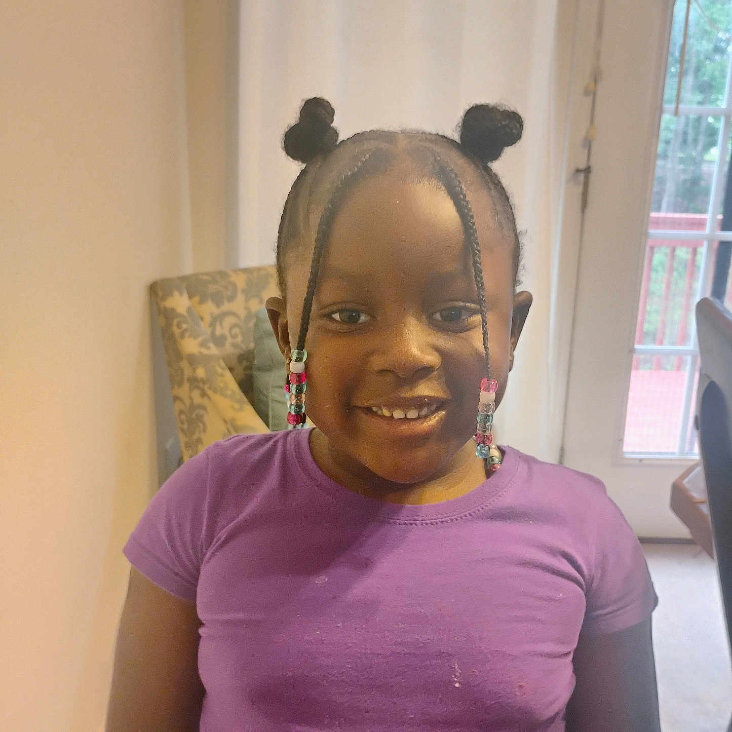 Devonna joined the competition — help win amazing prizes! beads, braids, casual_clothing, chair, child, cute, door, furniture, girl, hairstyle, happy, home, indoor, natural_light, person, portrait, purple_shirt, smiling, window, young