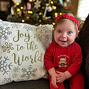 Emberlynn joined the competition — help win amazing prizes! baby, child, smiling, red_clothing, headband, christmas_tree, holiday, decorations, couch, pillow, text, joy_to_the_world, indoors, face, happy, festive, teddy_bear, sitting, cute, bright_eyes