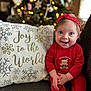 baby, child, smiling, red_clothing, headband, christmas_tree, holiday, decorations, couch, pillow, text, joy_to_the_world, indoors, face, happy, festive, teddy_bear, sitting, cute, bright_eyes