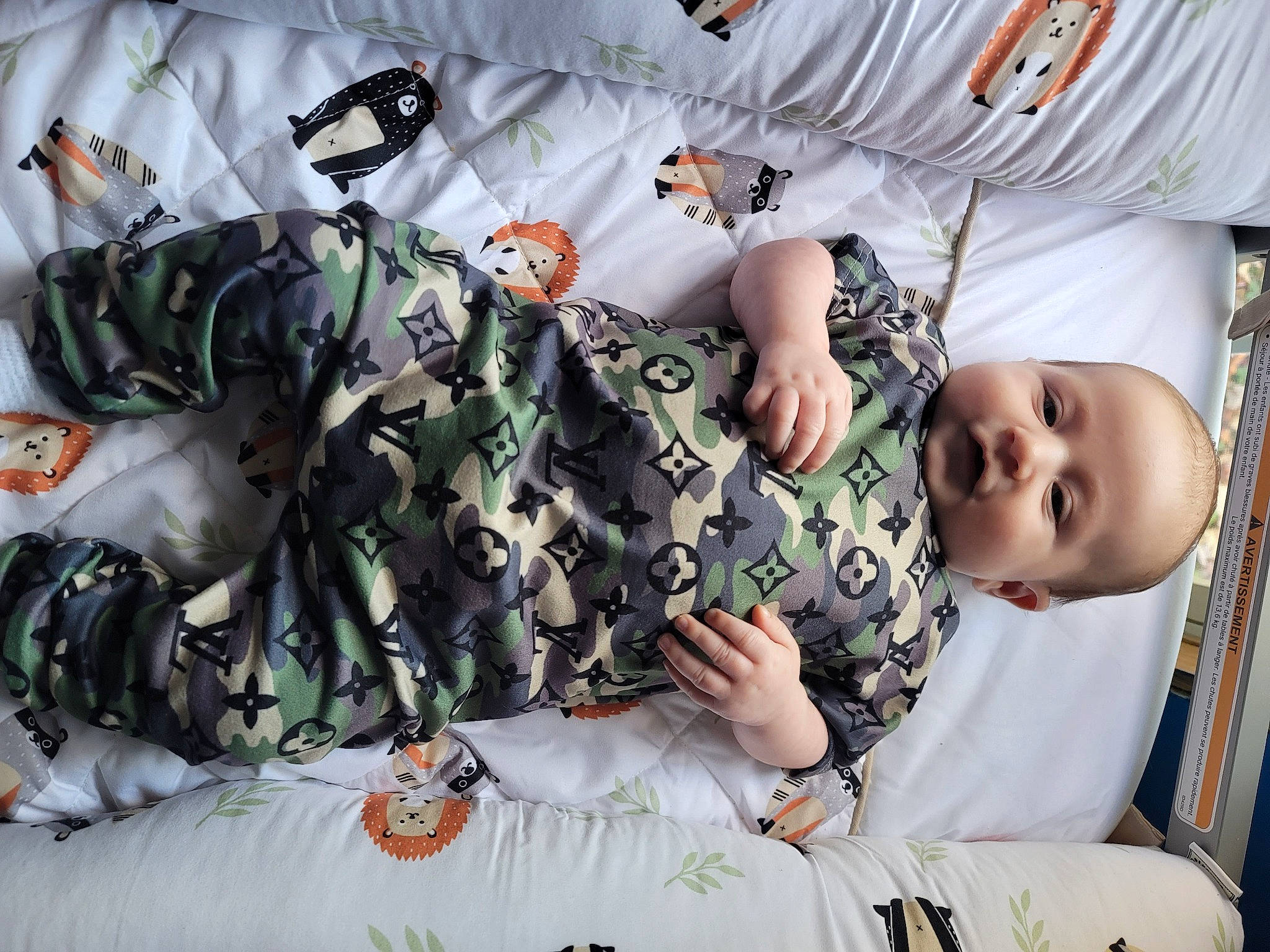 Zaidyn is registered to the contest to win money with this photo: baby, baby_products, baby_toddler_clothing, camouflage, child, comfort, cool, gesture, happy, linens, mammal, military_camouflage, military_person, military_uniform, pattern, person, room, sleeve, t_shirt, toddler
