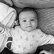 Elvis participe au concours pour gagner de l'argent avec cette photo : baby, infant, child, onesie, fox_pattern, black_and_white, portrait, face, eyes, hand, blanket, texture, cute, expression, lying_down, soft_lighting, indoor, comfort, tenderness, clothing