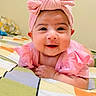 Doha Mehrish is registered to the contest to win money with this photo: baby, child, pink_clothing, headband, smile, face, lying_down, blanket, colorful, indoors, cute, portrait, infant, happy, young_child, cheeks, hands, bedroom, soft_light, adorable