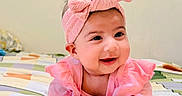 Doha Mehrish is registered to the contest to win money with this photo: baby, child, pink_bow, headband, smiling, tummy_pose, bedspread, colorful, checkered, indoor, cute, happy, infant, clothing, portrait, face, person, wall, soft_lighting, resting