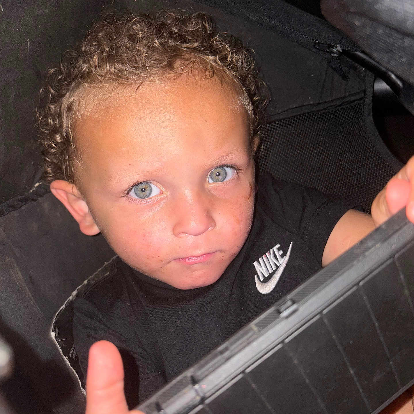 Zayden joined the competition — help win amazing prizes! black_shirt, blue_eyes, boy, casual_clothing, child, childhood, closeup, curious, curly_hair, cute, expression, face, grip, holding_object, indoor, looking_at_camera, nike_logo, person, portrait, young
