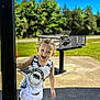 Zayden is registered to the contest to win money with this photo: child, toddler, curly_hair, tank_top, shorts, outdoor, park, barbecue_grill, greenery, sunny, playful, smiling, concrete, pole, summer, daylight, clothing, person, nature, recreation