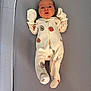 baby, infant, onesie, mittens, sleeping_bed, gray_background, cute, fruit_pattern, vegetable_pattern, newborn, soft_fabric, lying_down, cozy, small_hands, footed_pajamas, child, portrait, indoors, peaceful, adorable