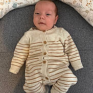 Marius participe au concours pour gagner de l'argent avec cette photo : baby, infant, onesie, striped_clothing, couch, pillow, bunny_pattern, indoor, face, socks, wooden_floor, buttoned_clothing, person, cute, portrait, child, relaxed, soft_toys, home, seated