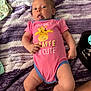 baby, infant, onesie, pink_clothing, giraffe_graphic, tongue_out, blanket, purple_blanket, diaper, pacifier, cute, playful, lying_down, human, child, soft_texture, hand, foot, indoor, casual