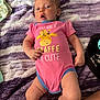 baby, infant, onesie, giraffe_graphic, pink_clothing, purple_blanket, soft_texture, curious_expression, lying_down, human, child, cute, indoor, skin, hand, face, leg, foot, newborn, blanket