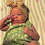 baby, infant, headband, bow, green_clothing, floral_pattern, blanket, striped, hand, face, expression, cute, relaxed, lying_down, skin, person, child, indoors, decor, pink_heart