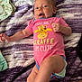 baby, infant, onesie, pink_clothing, giraffe_print, blanket, purple, white, smiling, lying_down, diaper, cute, playful, child, face, hand, foot, person, soft_texture, happy
