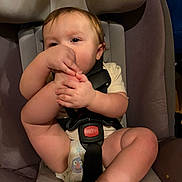 Kelsey joined the competition — help win amazing prizes! baby, child, infant, car_seat, sitting, indoors, face, hands, feet, toes, barefoot, diaper, shirt, harness, seat_belt, curious, portrait, close_up, automotive, family