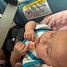 baby, sleeping, car_seat, blanket, infant, child, safety_belt, face, hand, soft, pink, closeup, peaceful, resting, young_child, apparel, seatbelt, warning_label, comfort, portrait
