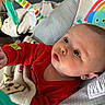 baby, infant, red_clothing, blanket, baby_seat, toy, colorful_toy, elephant_pattern, rainbow_pattern, curious, indoors, child, face, portrait, soft_texture, couch, closeup, focus, cute, young_child