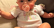 Kelsey joined the competition — help win amazing prizes! baby, infant, pacifier, headband, onesie, couch, indoor, child, cute, pastel_colors, first_easter, chubby_cheeks, feet, hands, soft_lighting, relaxing, smiling, portrait, young_child, sitting