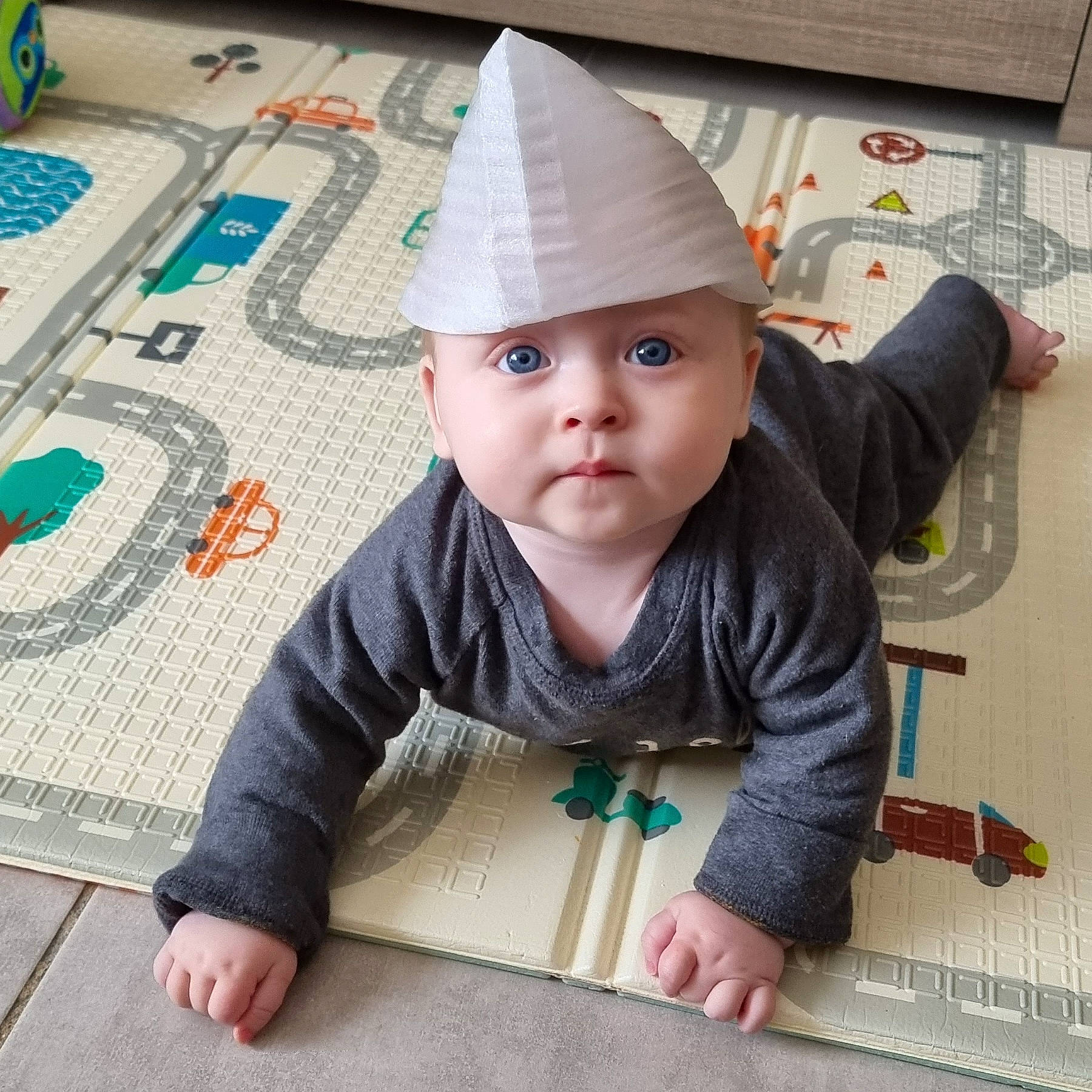 Mattéo participe au concours pour gagner de l'argent avec cette photo : baby, baby_toddler_clothing, blue, cap, child, cone, costume_hat, face, fashion_accessory, floor, flooring, fun, headwear, outerwear, pattern, person, play, product, sitting, sleeve