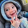 Jordan is registered to the contest to win money with this photo: baby, blanket, blue, car_seat, child, closeup, crocheted, cute, face, hand_gesture, happy, hoodie, indoors, infant, knitted, person, portrait, seatbelt, smiling, warm_clothing