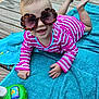 baby, blue_towel, child, colorful, cute, feet, fun, hand, happy, infant, lying_down, outdoor, pink, playtime, smiling, striped_clothing, summer, sunglasses, toy, wooden_deck