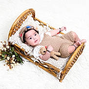 Advik joined the competition — help win amazing prizes! baby, infant, wicker_bed, knitted_clothing, crocheted_toy, cap, bracelet, flowers, soft_texture, white_background, portrait, cute, child, resting, indoor, cozy, smiling, decor, toddler, sleeping_area