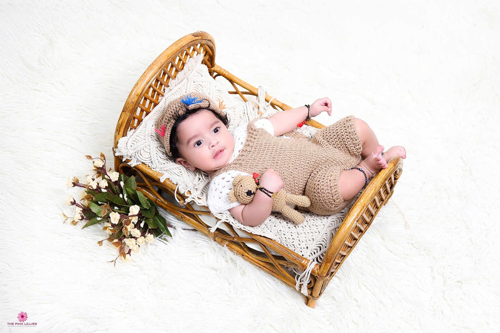 Advik joined the competition — help win amazing prizes! baby, infant, wicker_bed, knitted_clothing, crocheted_toy, cap, bracelet, flowers, soft_texture, white_background, portrait, cute, child, resting, indoor, cozy, smiling, decor, toddler, sleeping_area