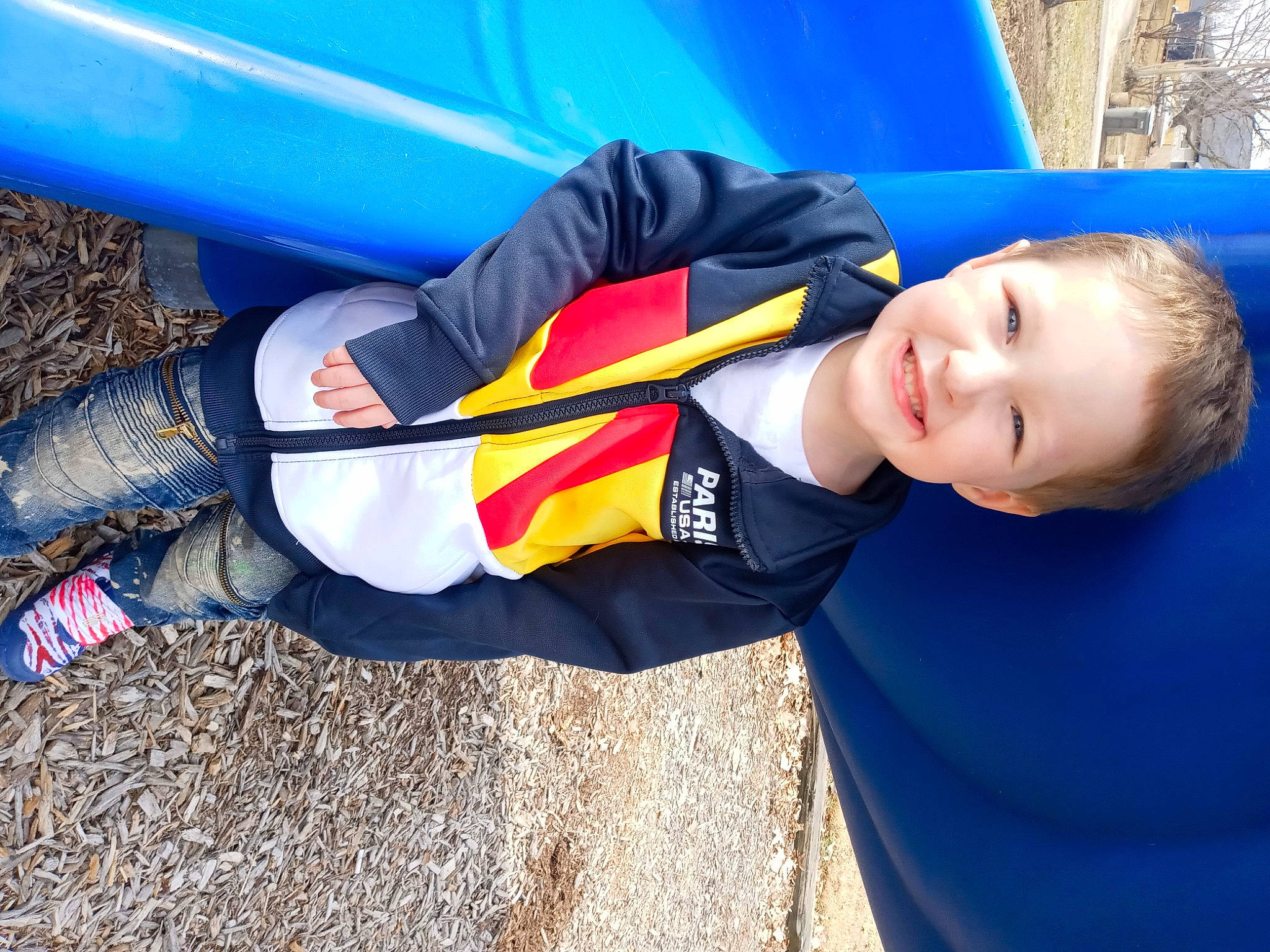 Brentley is registered to the contest to win money with this photo: blue, child, city, electric_blue, fun, grass, happy, hat, human_leg, joy, leisure, outdoor_play_equipment, person, personal_protective_equipment, play, recreation, sitting, smile, t_shirt, thigh