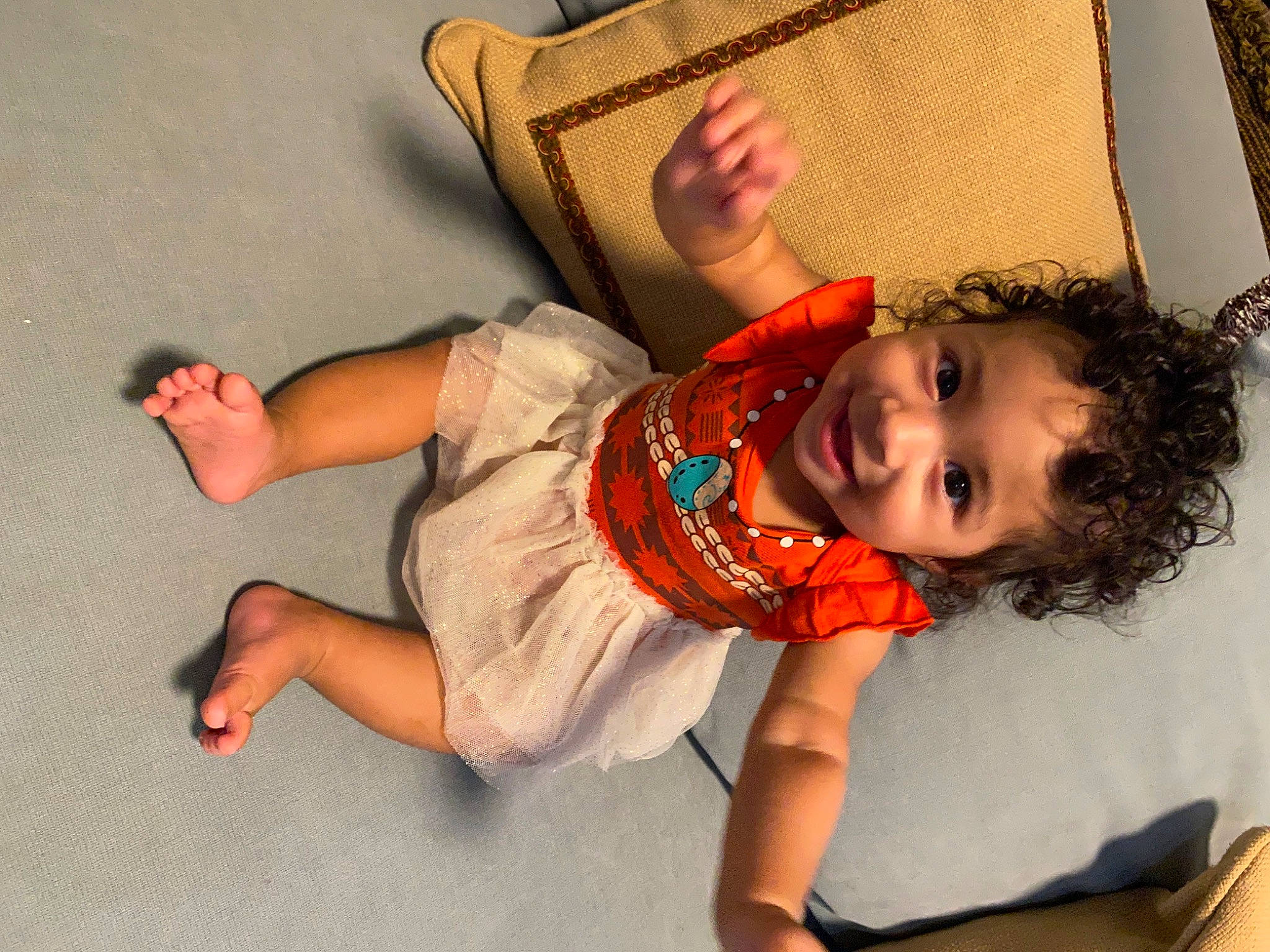 Eliana is registered to the contest to win money with this photo: arm, baby_toddler_clothing, child, comfort, elbow, fun, happy, human_body, human_leg, joy, knee, leisure, mouth, orange, person, sitting, smile, sock, thigh, toddler