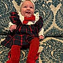 baby, child, clothing, couch, cute, decor, fabric, happy, headband, indoor, infant, patterned_couch, person, plaid_dress, portrait, red_bow, red_tights, sitting, smiling, tongue_out