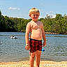 child, boy, beach, lake, water, sand, swim_shorts, sunny, outdoor, nature, trees, person, floating, inner_tube, summer, barefoot, sky, clouds, recreation, daytime