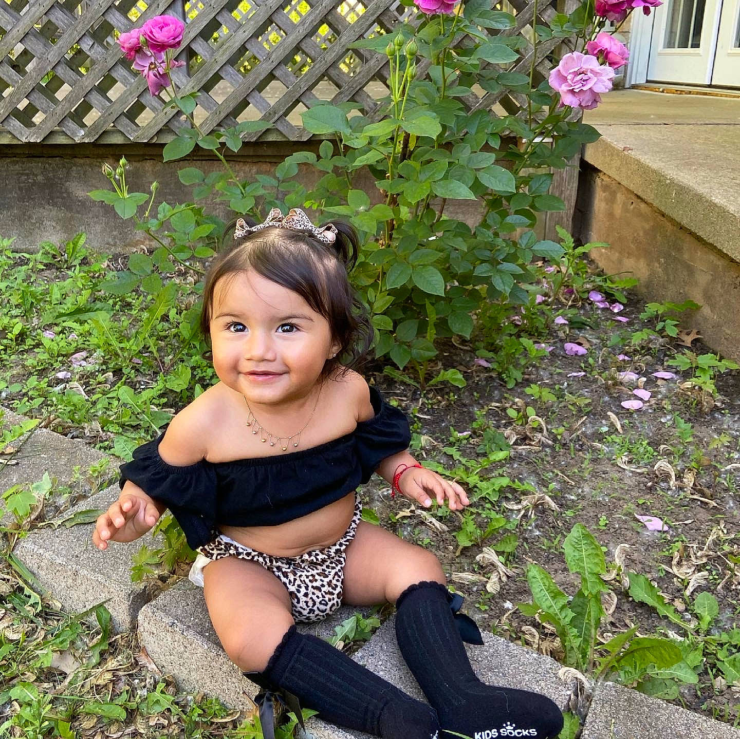 Lilliana is registered to the contest to win money with this photo: baby_toddler_clothing, botany, fawn, flower, grass, groundcover, happy, human_leg, joy, knee, leisure, people_in_nature, person, petal, pink, plant, purple, shrub, smile, sock