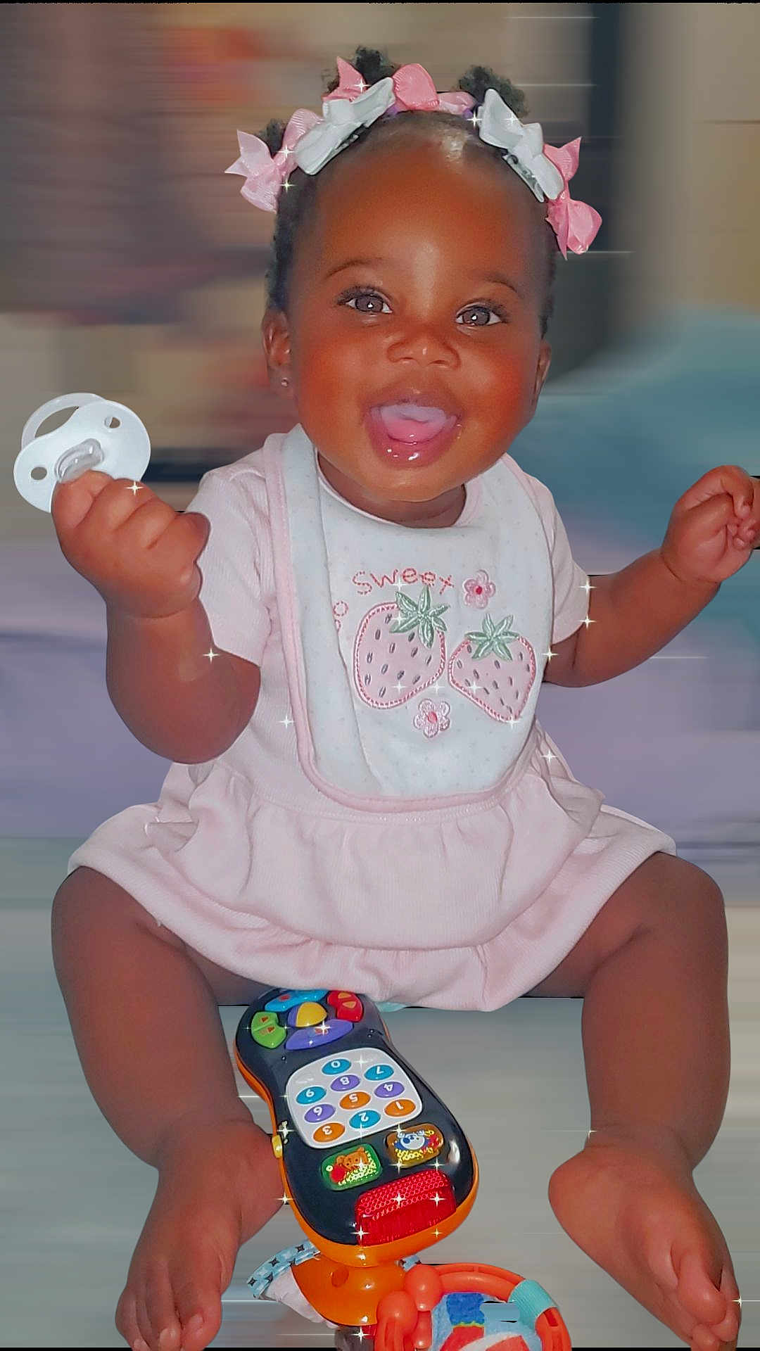 Kardiaye joined the competition — help win amazing prizes! baby, child, smiling, pacifier, bows, hair_accessories, pink_clothing, bib, toy_phone, sitting, happy, indoors, cute, infant, playful, portrait, sparkles, dark_skin, short_hair, cheerful