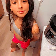 Nicole is registered to the contest to win money with this photo: appliance, barefoot, blender, brown_hair, child, countertop, face, girl, gray_top, home, indoors, kitchen, long_hair, person, pink_shorts, portrait, selfie, smiling, standing, wood_floor