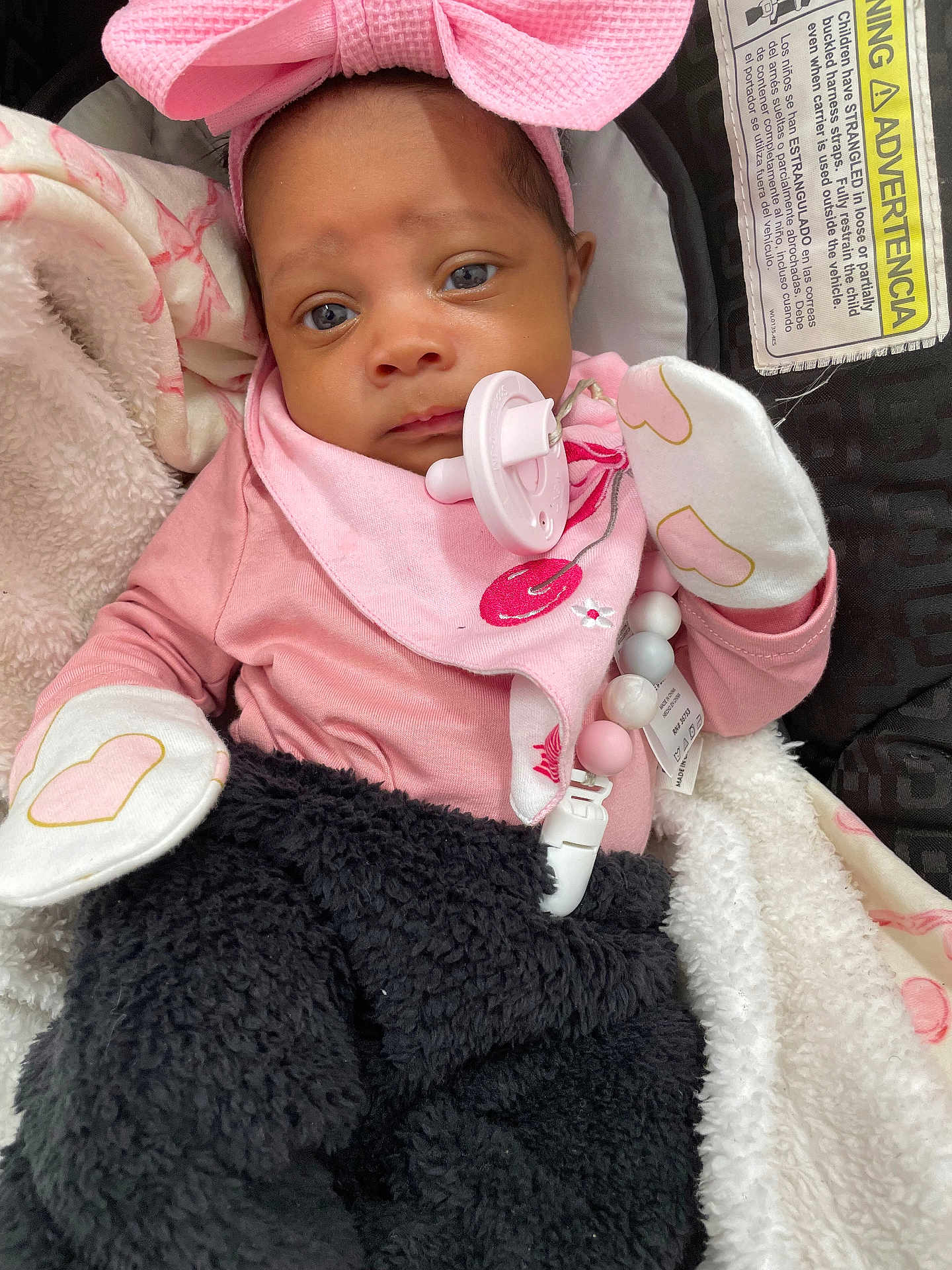Amoura is registered to the contest to win money with this photo: baby, infant, pink_bow, pacifier, mittens, blanket, car_seat, clothing, face, person, cute, newborn, portrait, soft, cozy, warm, indoor, child, baby_girl, accessory