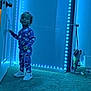 Khalil is registered to the contest to win money with this photo: toddler, child, pajamas, blue_lighting, led_lights, door, carpet, indoor, standing, curious, sneakers, space_theme, room, young_child, person, footwear, hair, wall, reflection, lighting