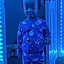 Khalil joined the competition — help win amazing prizes! child, pajamas, blue_light, door, carpet, indoor, toy, string_lights, space_theme, person, wall, room, hand, standing, clothing, face, head, expression, lighting, door_handle