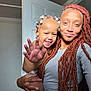 toddler, child, woman, person, smile, happy, hair_beads, dreadlocks, indoor, door, gray_shirt, skin, hand, holding, portrait, family, cute, playful, closeup, light