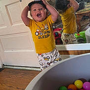 Benjamin is registered to the contest to win money with this photo: child, toddler, baby, smiling, indoors, portrait, standing, cap, yellow_shirt, pajamas, toy, ball_pit, colorful_balls, mirror, reflection, playroom, door, wood_floor, happy, photography