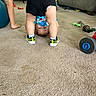 Benjamin is registered to the contest to win money with this photo: child, toddler, upside_down, playful, smiling, face, indoor, living_room, carpet, toy, sneakers, shorts, shirt, socks, furniture, sofa, wheel, playroom, acrobat, portrait