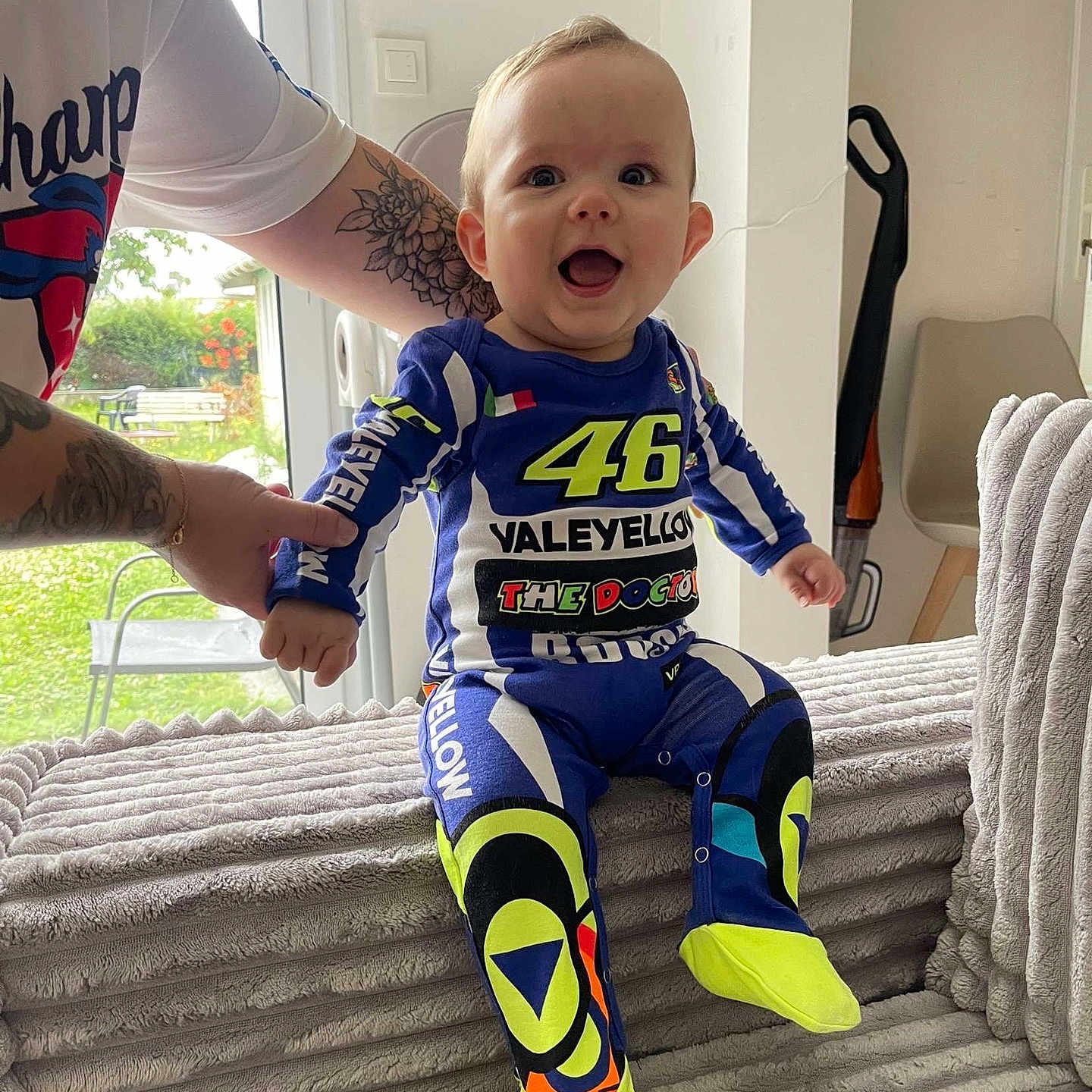 Lévy participe au concours pour gagner de l'argent avec cette photo : baby, bright, child, clothing, colorful, couch, furniture, hand, happy, home, indoor, joy, outfit, person, plush, sitting, smile, support, tattoo, window