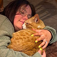 Bandit joined the competition — help win amazing prizes! affection, cat, close_up, comfort, cozy, cuddle, face, fleece_jacket, floor, glasses, hand, hug, indoor, orange_tabby, person, pet, relaxation, ring, warm_lighting, yellow_nails